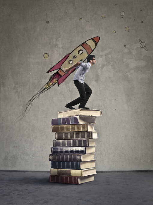Man standing on a stack of books with a hand-drawn rocket strapped to his back.